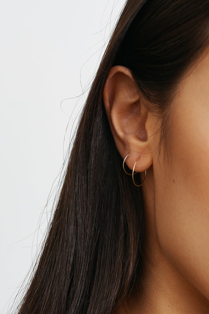 Cropped view of models ear 14K 301 Mini Hoops Earrings paired with size 302 Bagatiba