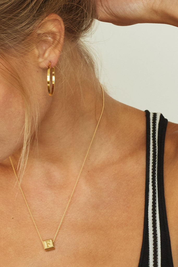 close up Model wearing "F" Letter Block letters on spiral chain paired with simple gold hoops Bagatiba