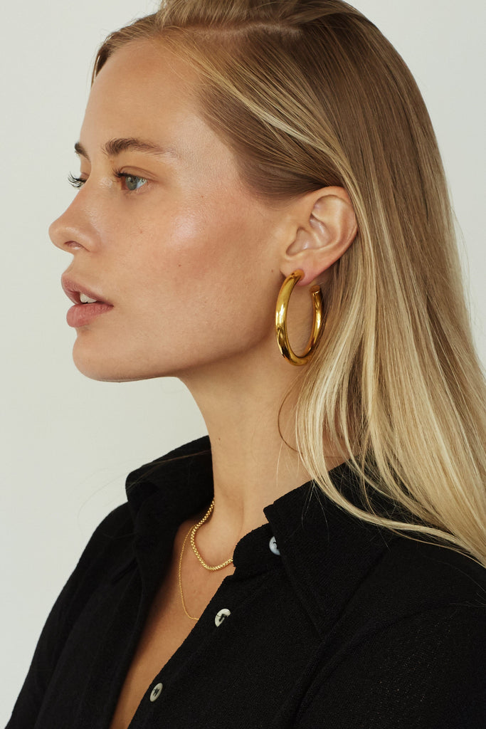 Model profile view wearing Gold Hollow Hoops Earrings Bagatiba