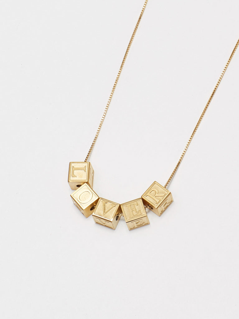 Close up flat lay of Letter blocks "L" "O" "V" "E" "R" on vintage square chain bagatiba