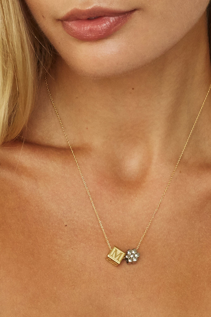 close up on model of "M" Letter Block letters and silver flower bead  Bagatiba