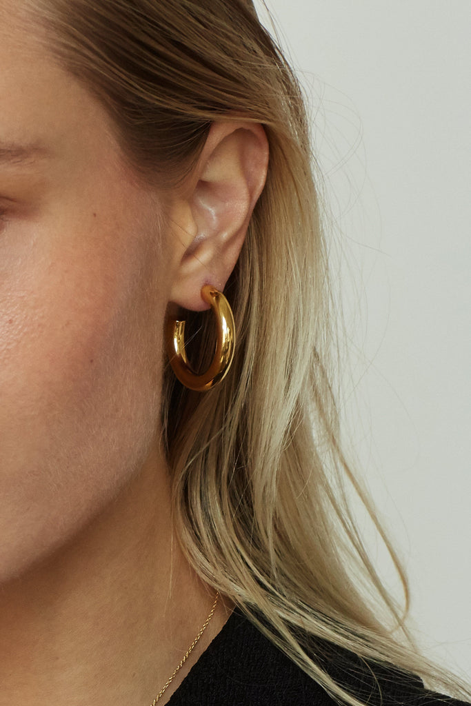 Detail view of model's ear wearing Mini Gold Hollow Hoops Earrings Bagatiba