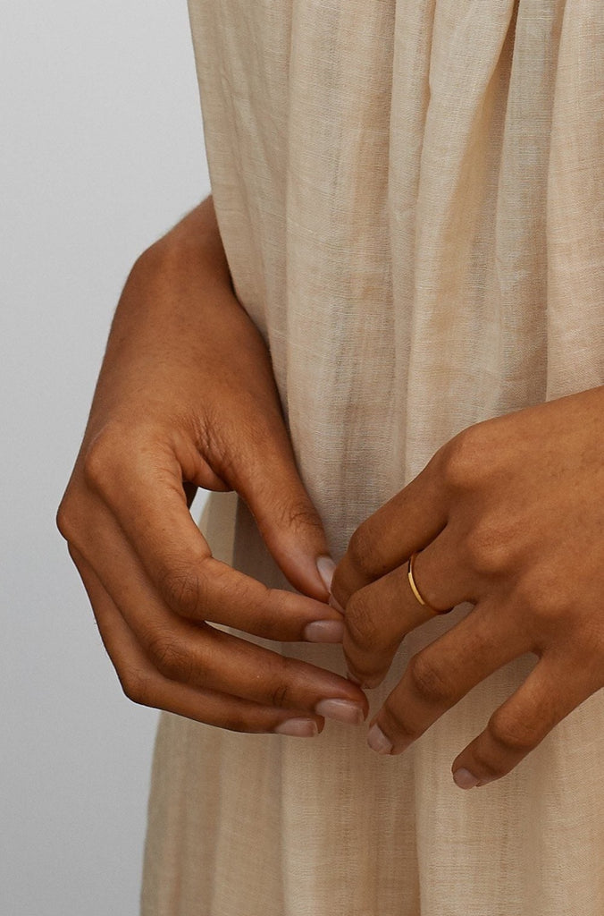 Full view of model wearing Polished Gold Ring and oversized gold hoops with a linen dress