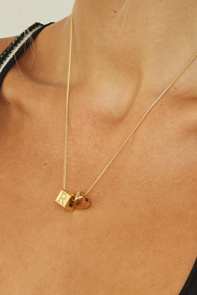 cropped view on model "R" Letter Block letter with gold heart bead on spiral chain  Bagatiba