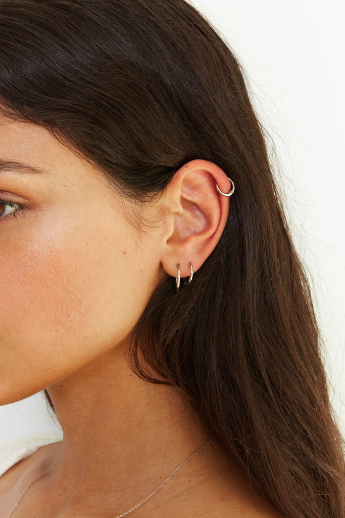 Set of Silver Eco Huggie Hoops Earrings detail view shown on model's ear  Bagatiba
