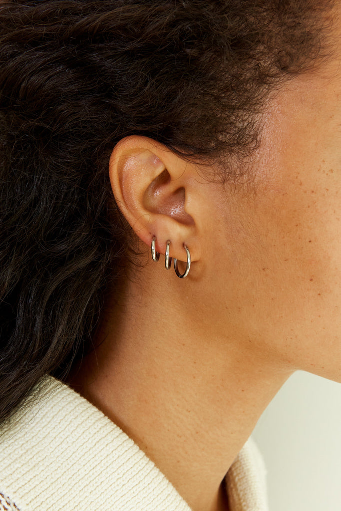 Side profile view of Set of Silver Eco Huggie Hoops Earrings on model's ear  Bagatiba