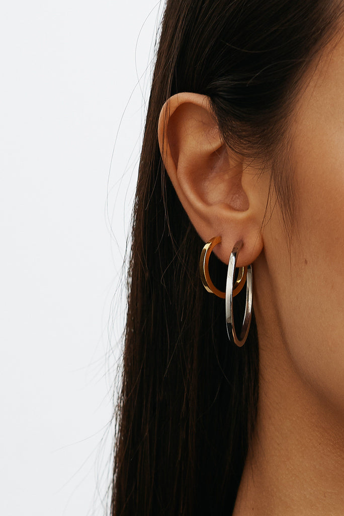 Cropped view on model's ear of Simple Silver Hoops and Small Simple Gold Hoops Earrings by Bagatiba