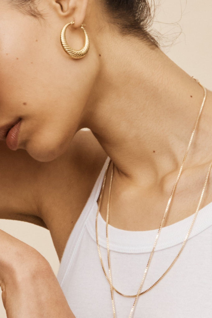 Side profile view of 2 models, 1 wearing the Small Spiral Hoops Earrings bagatiba