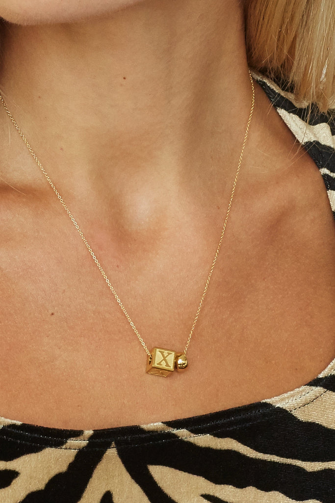 Cropped view on model "X" Letter Block letter and gold bead on chain  Bagatiba