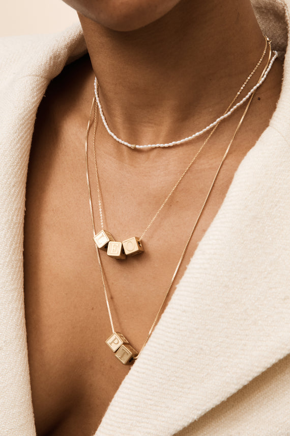 model wearing letter block collection and pearl necklace