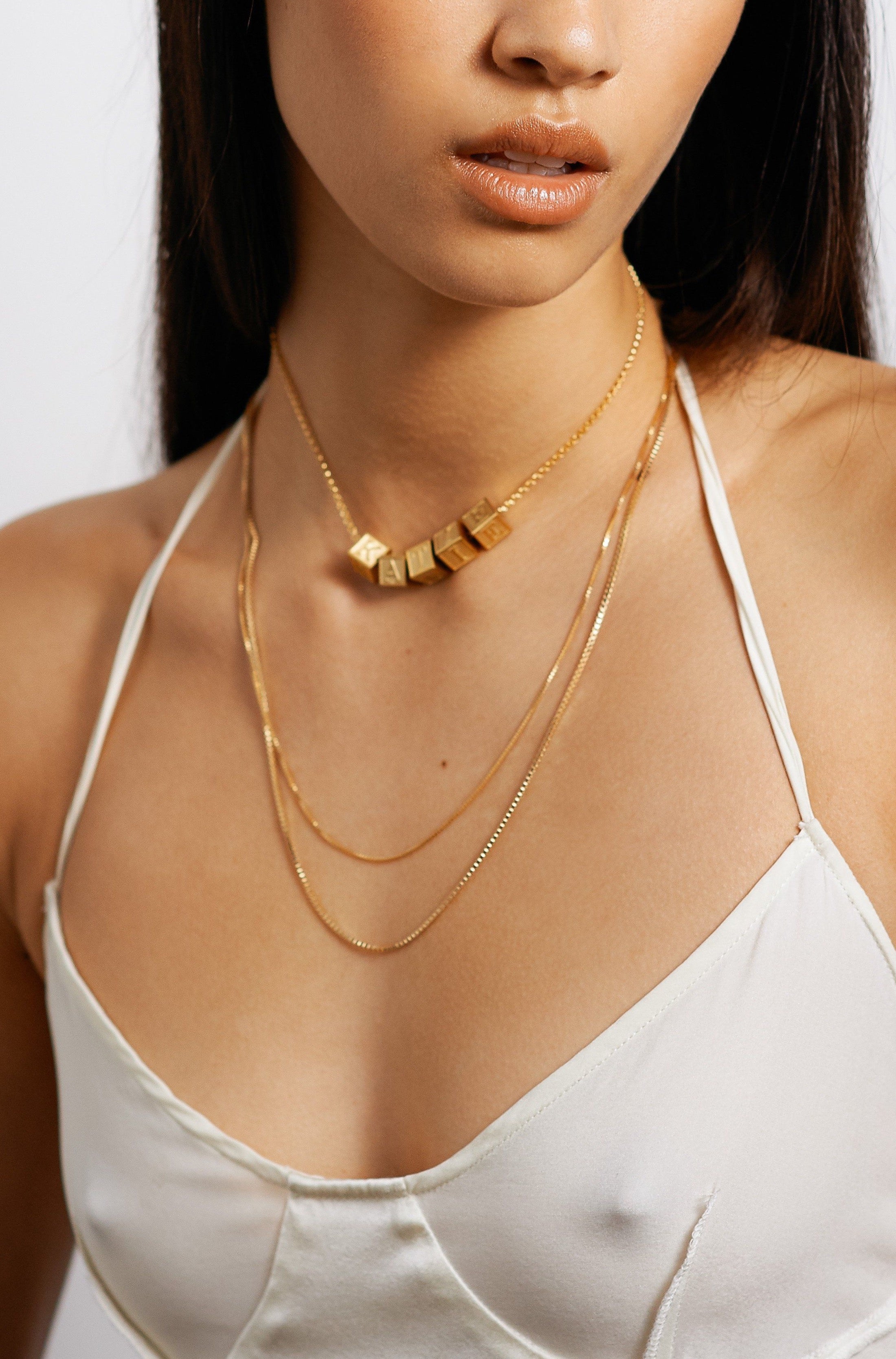 Model wearing 5 letter blocks on a choker chain paired with two longer chains bagatiba