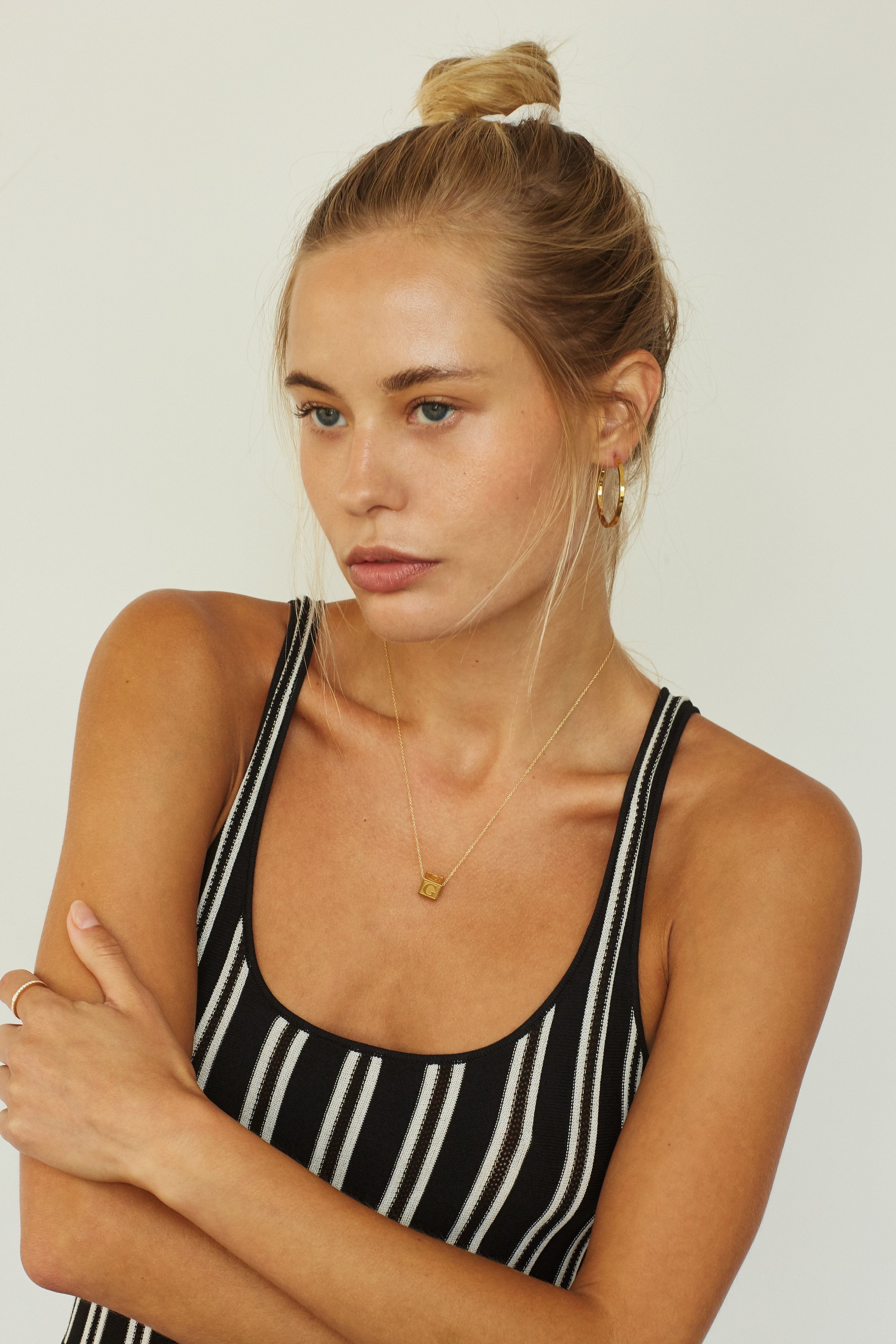Model wearing "G" Letter Block letters on simple chain paired with simple gold hoops Bagatiba 