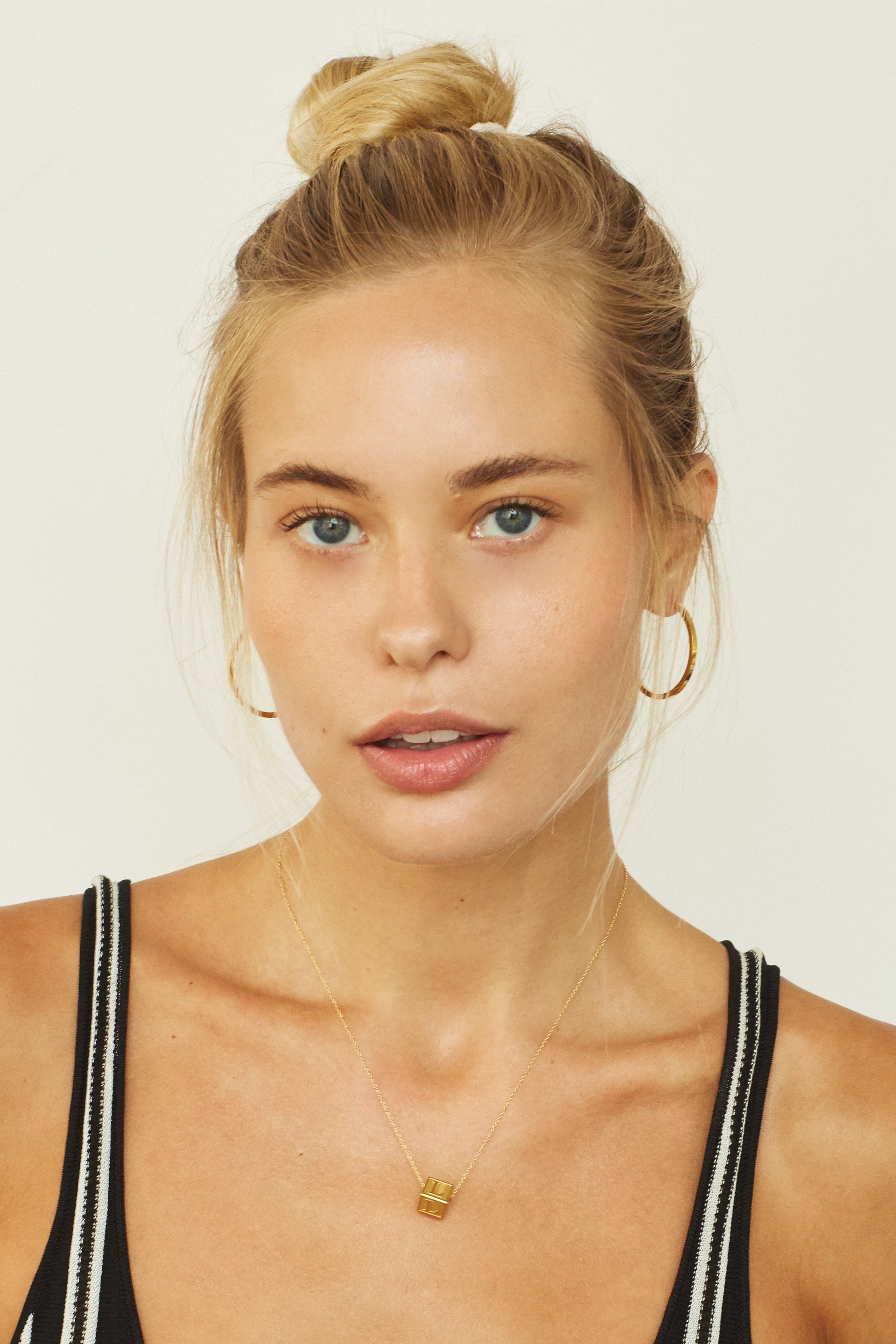Model wearing "L" Letter Block letter on simple chain paired with simple gold hoops  Bagatiba 