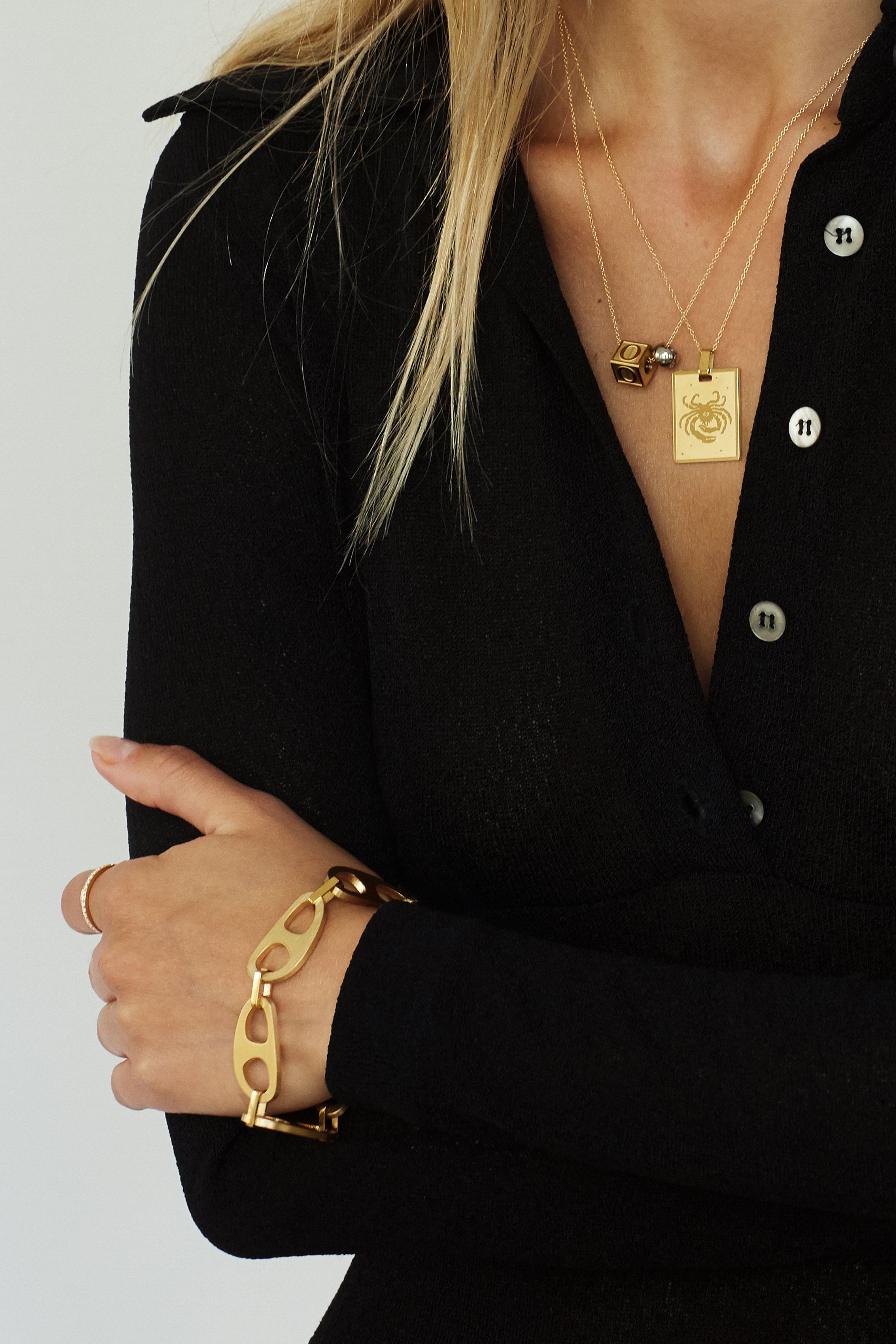 crop of model wearing "O" Letter Block letter on simple chain paired with zodiac charm on simple chain and brushed gold tab bracelet  Bagatiba 