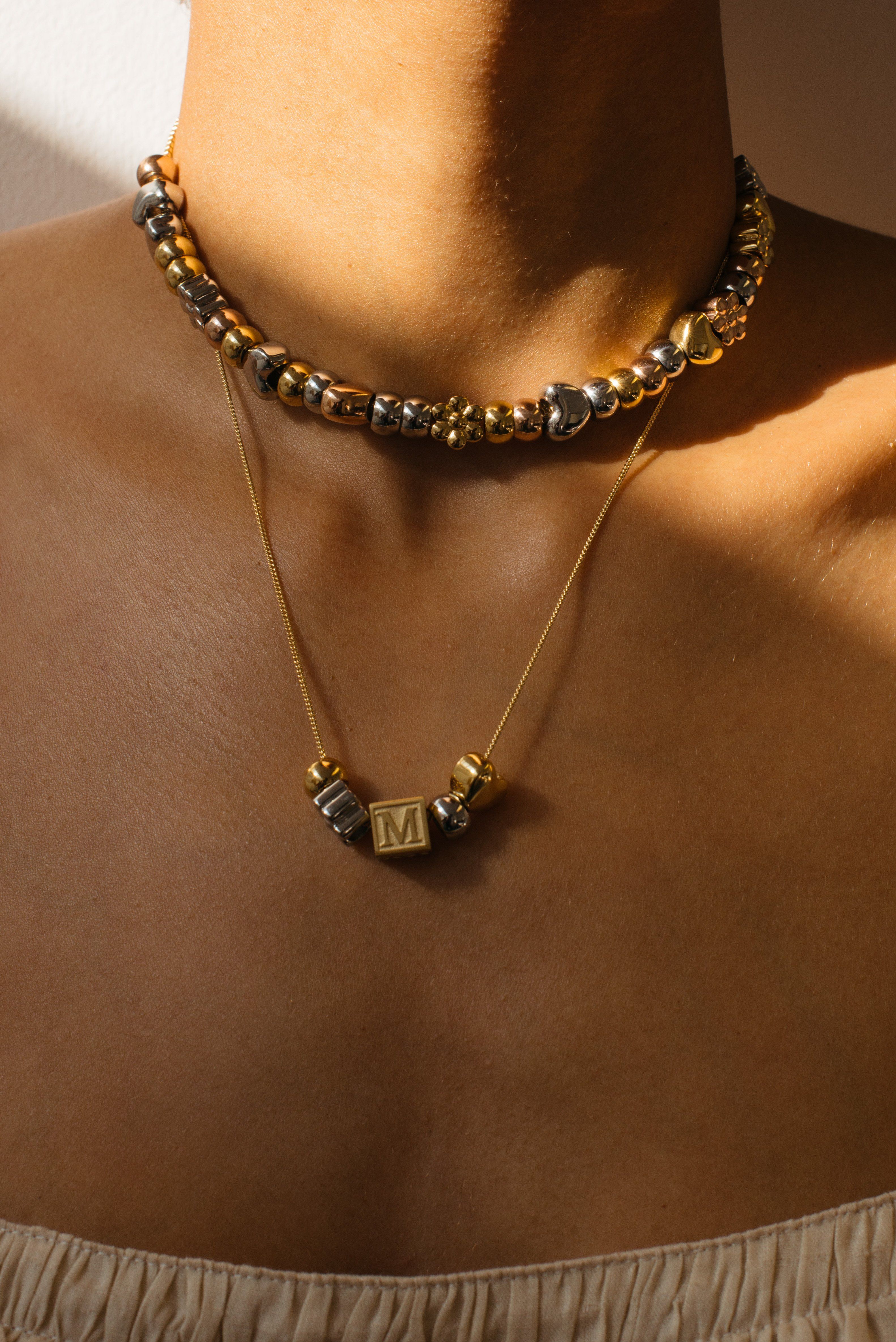 Crop view of model wearing multi bead choker paired with "M" Letter Block letters on chain Bagatiba 