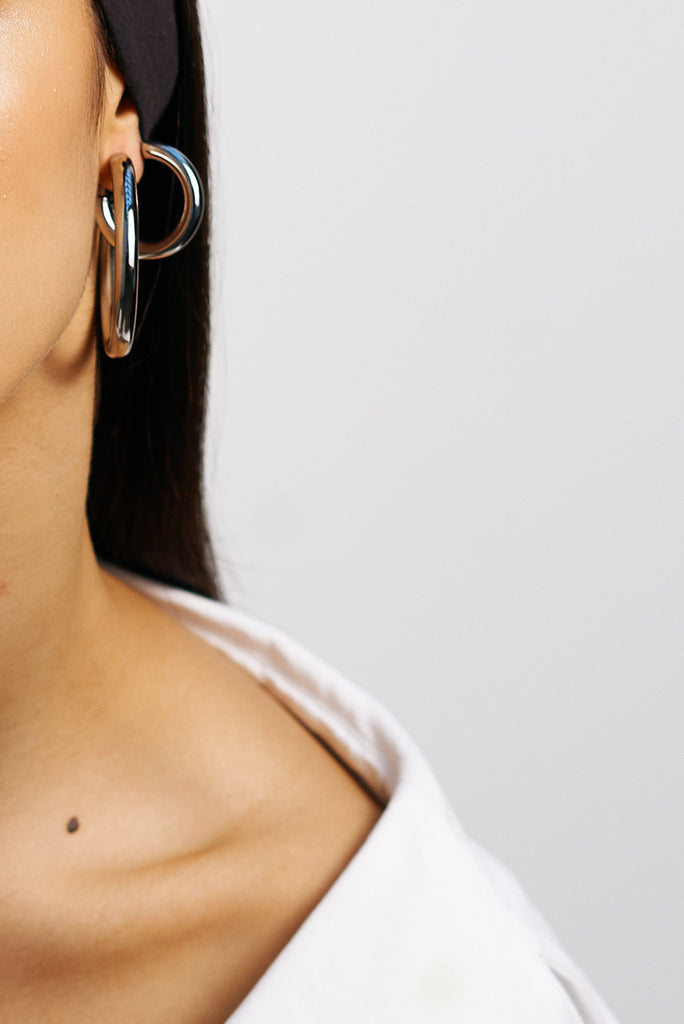 Detail view of model's ear styled with Silver Hollow Hoops and Mini Silver Hollow Hoops  Earrings Bagatiba 