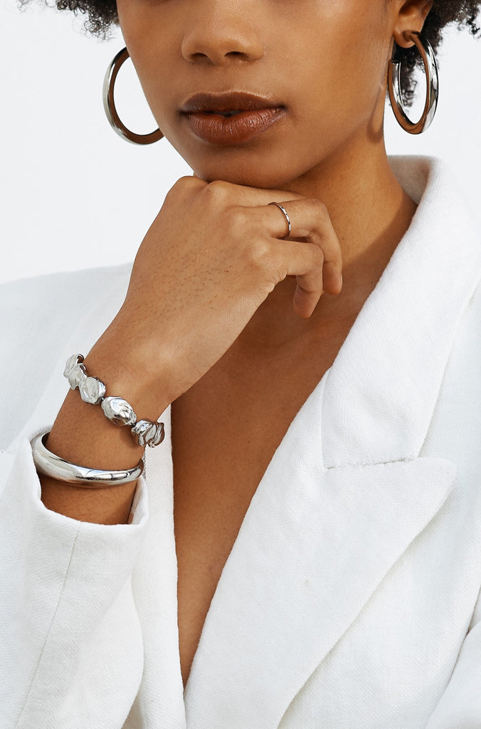 Model profile view wearing the Silver Pearl Bracelet, Silver Orb Cuff Bracelet and SIlver Hollow Hoops by  bagatiba 