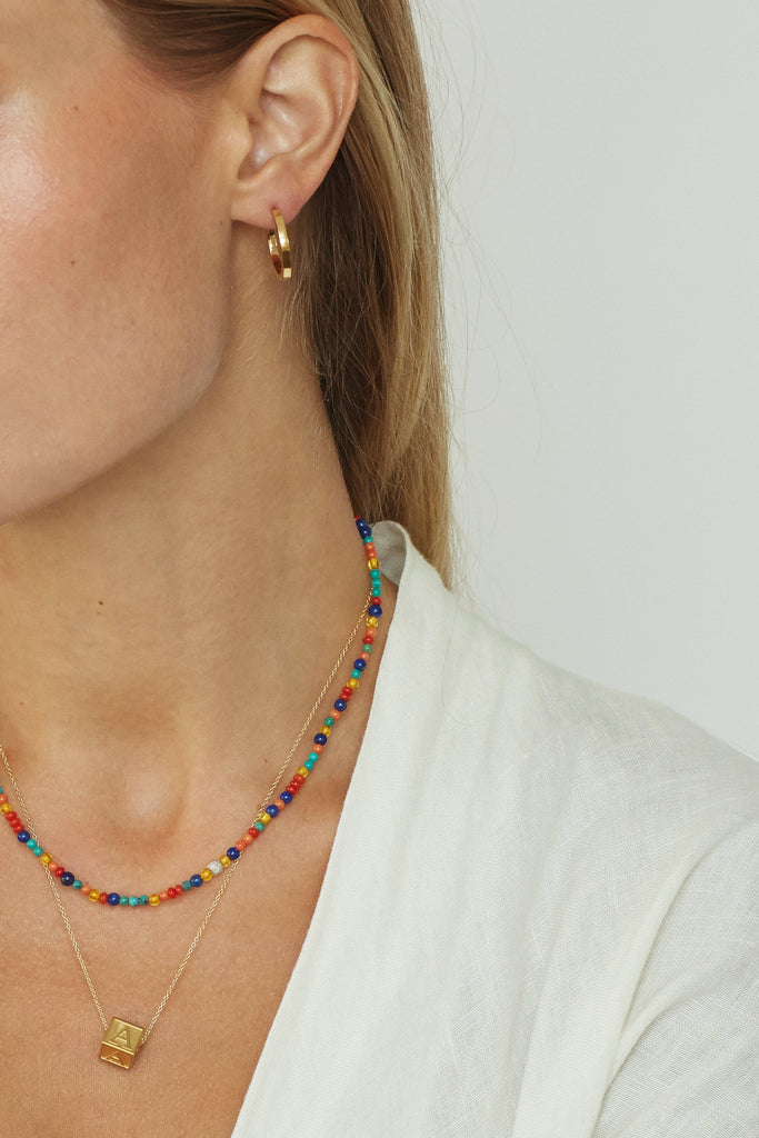 Detail view on model of Small Simple Gold Hoops, Multi-Bead Necklace and a Letter Block Charm by  Bagatiba 