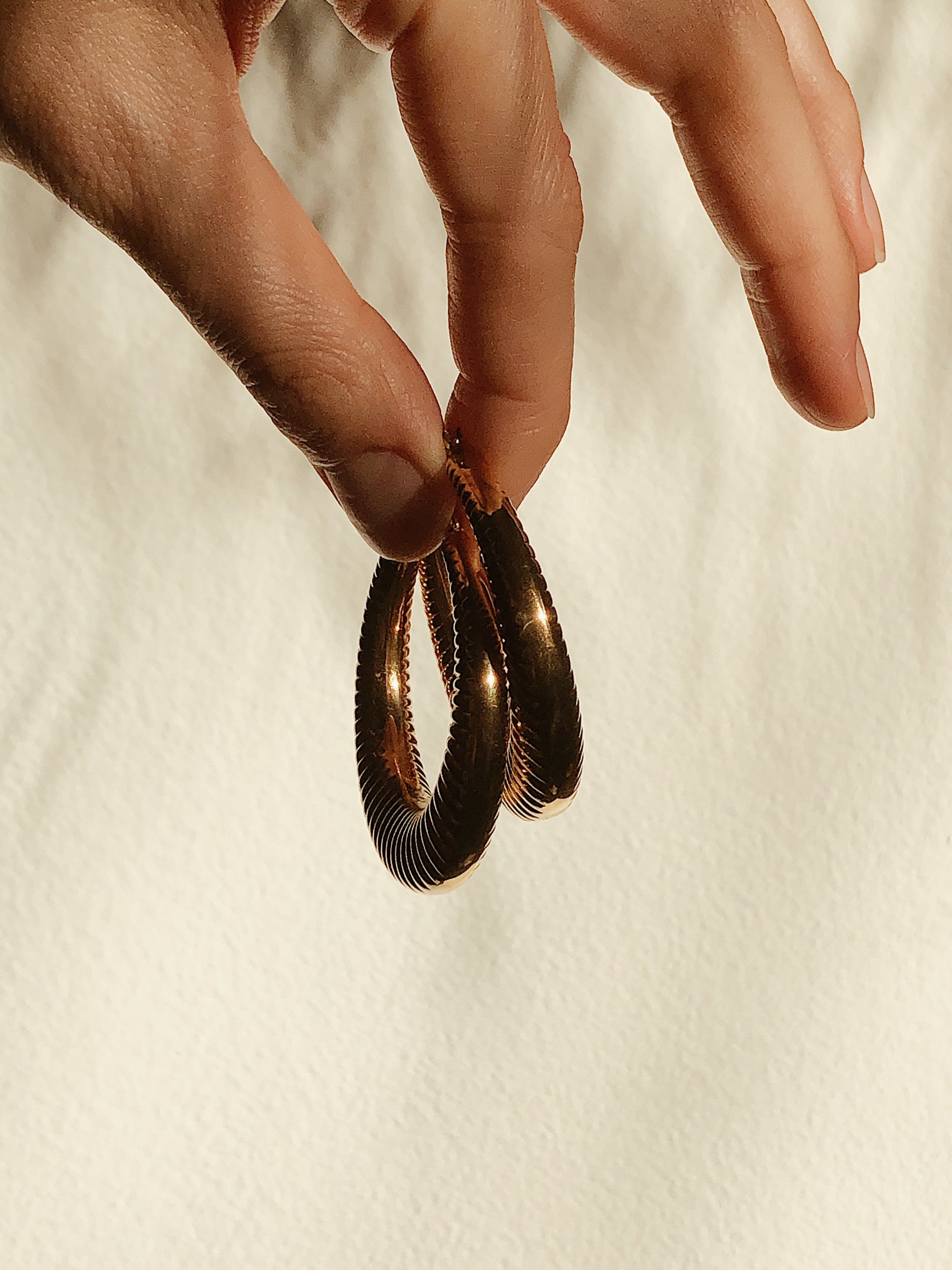 Spiral Hoops Earrings by bagatiba held in natural light 