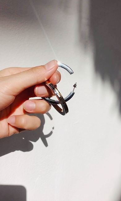 two tone flat hollow hoops earrings held in natural light