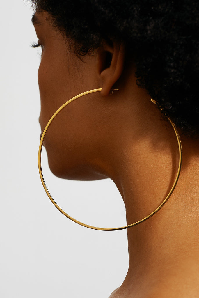 Detail view on model's ear of the XL Oversized Simple Gold Hoops Earrings Bagatiba 