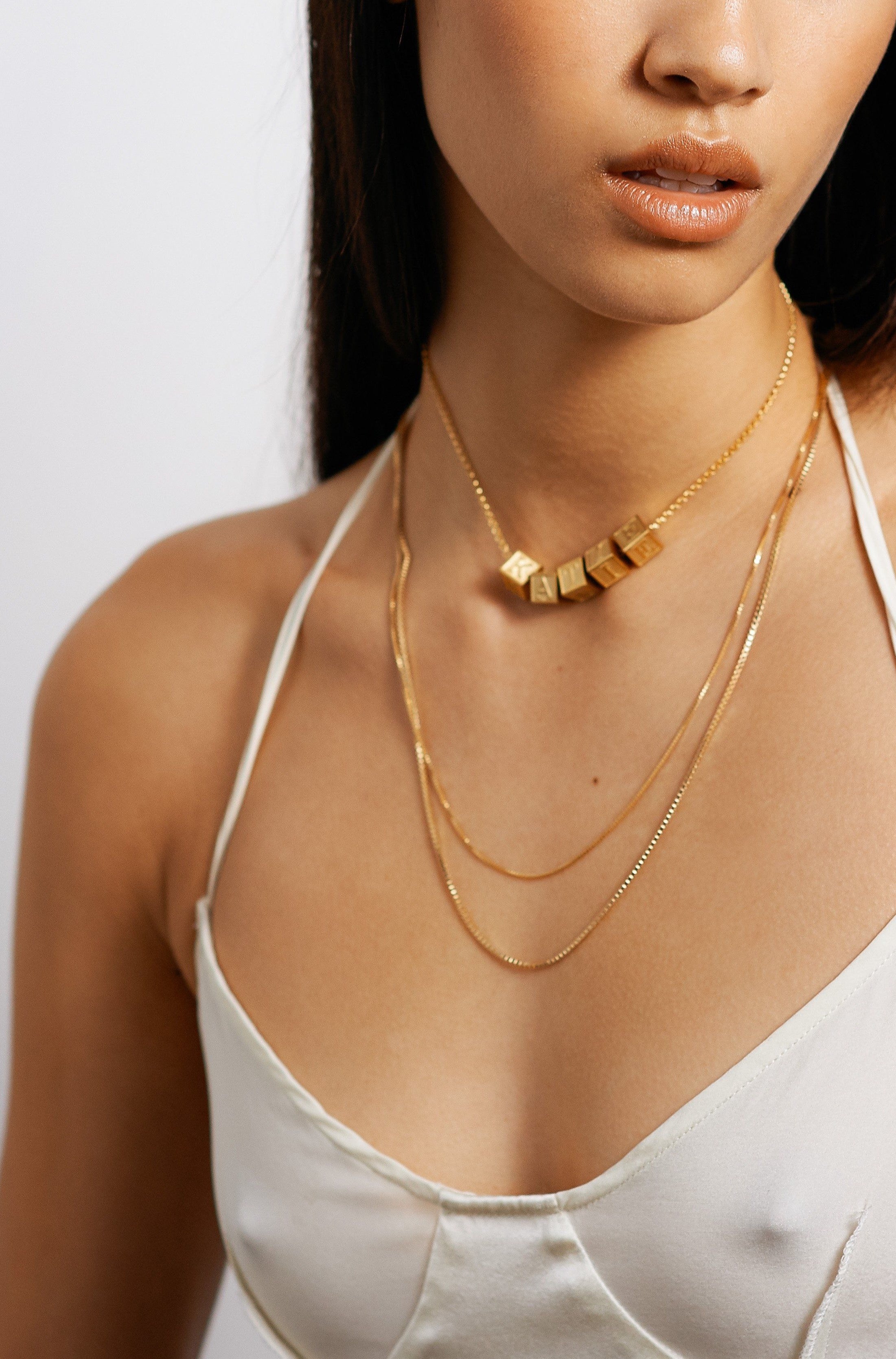 Full view model wearing 5 Letter Block letters on choker layered with two 22" chains Bagatiba