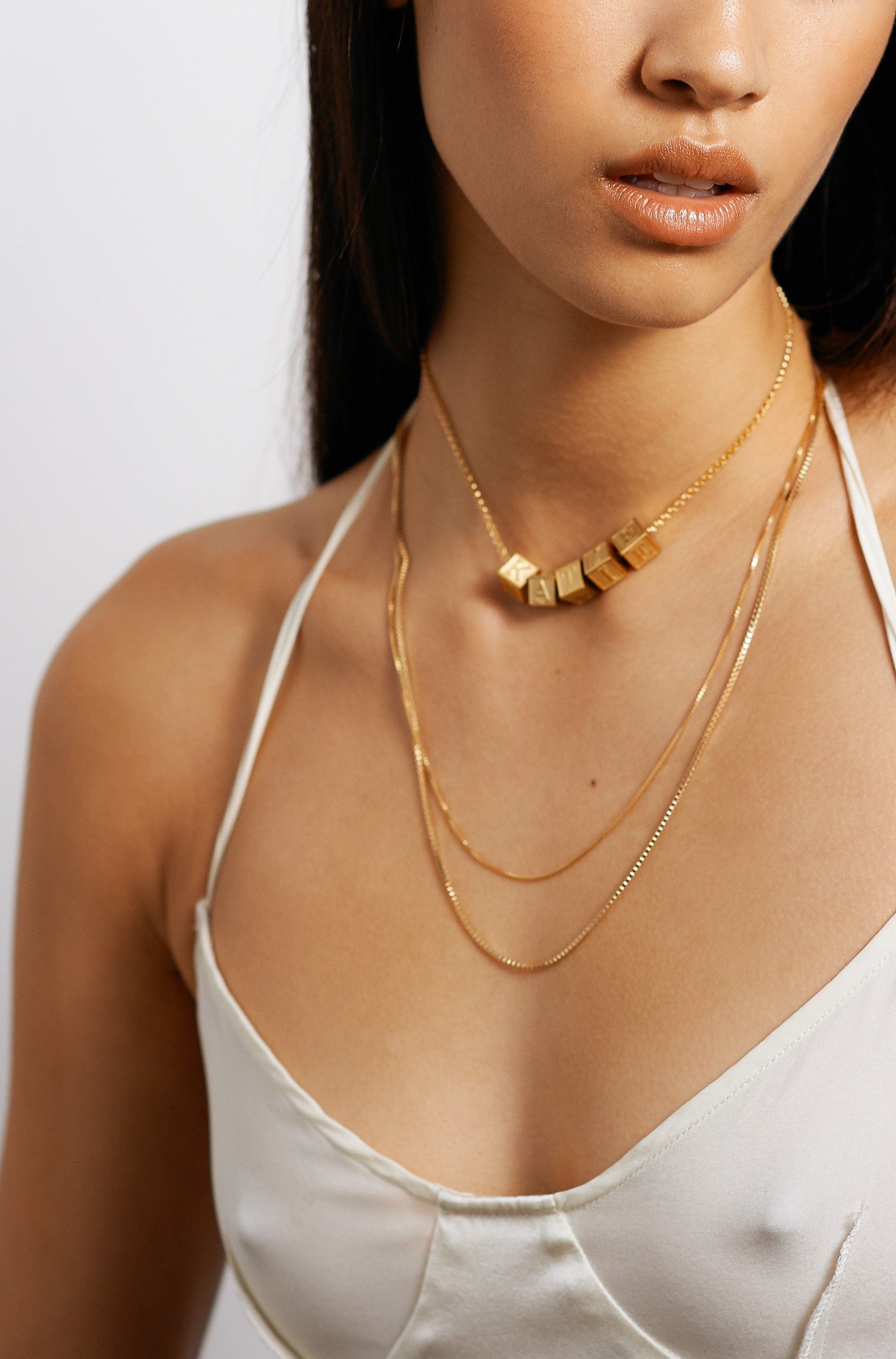 Model wearing 5 letter blocks on choker chain paired with two 22" chain styles bagatiba